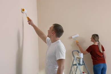 Photo of Couple painting wall in apartment during repair
