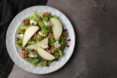 Photo of Delicious pear salad on dark textured table, top view. Space for text