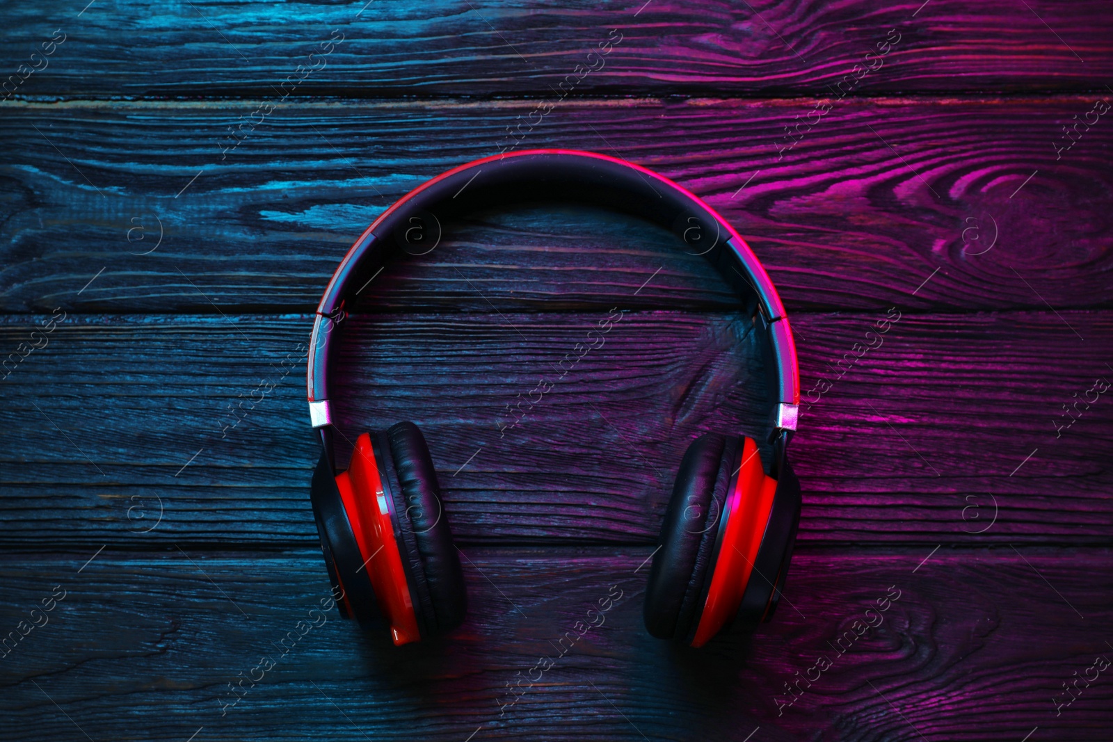 Photo of Stylish modern headphones with earmuffs on wooden background, top view