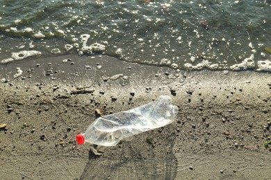 Photo of Used plastic bottle near water at beach. Environment pollution