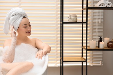 Photo of Happy woman taking bath with foam in tub indoors