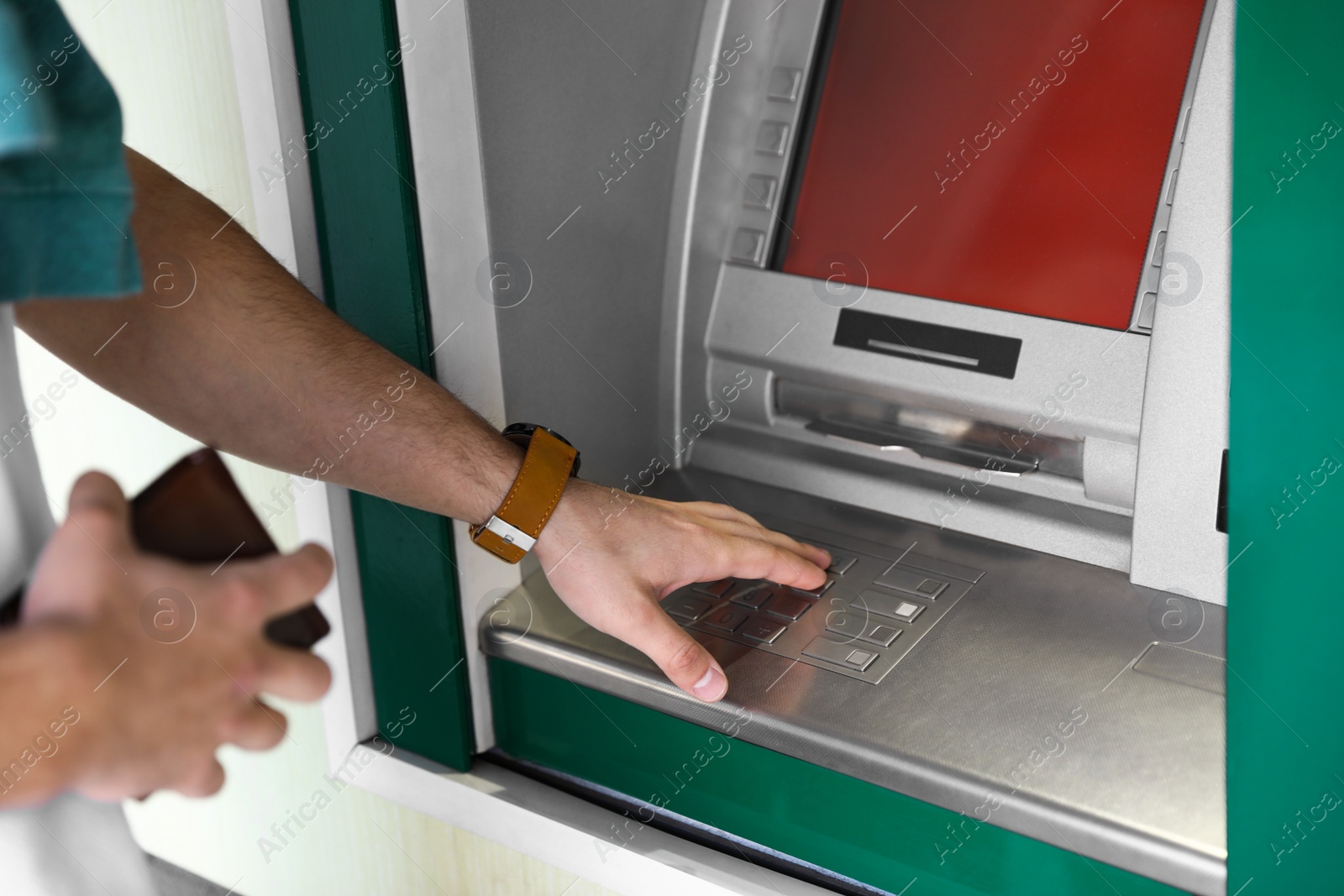 Photo of Man entering PIN code on cash machine keypad outdoors, closeup