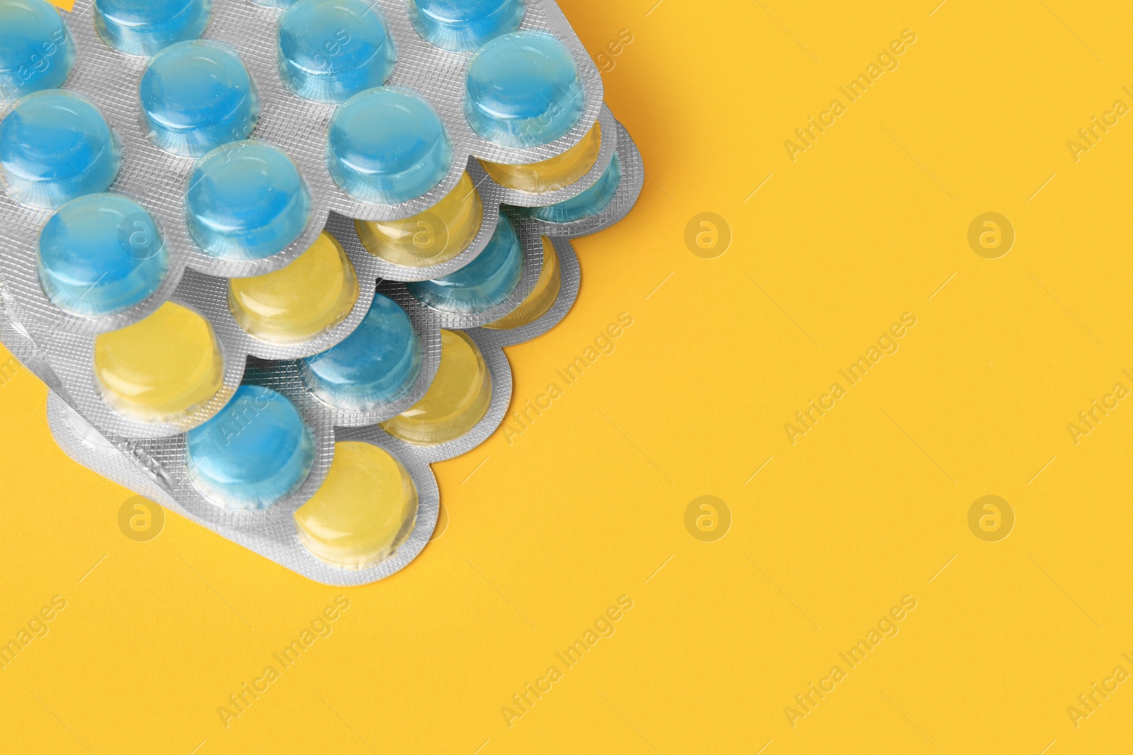 Photo of Blisters with cough drops on yellow background, closeup. Space for text