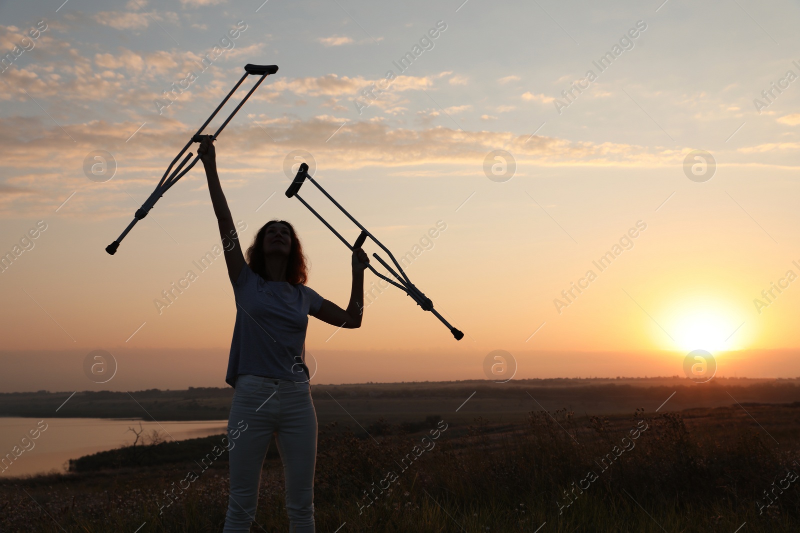 Photo of Woman holding axillary crutches outdoors at sunrise. Healing miracle