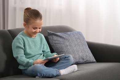 Photo of Little girl using tablet on sofa at home. Internet addiction
