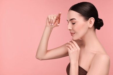 Photo of Beautiful young woman holding skincare ampoule on pink background. Space for text