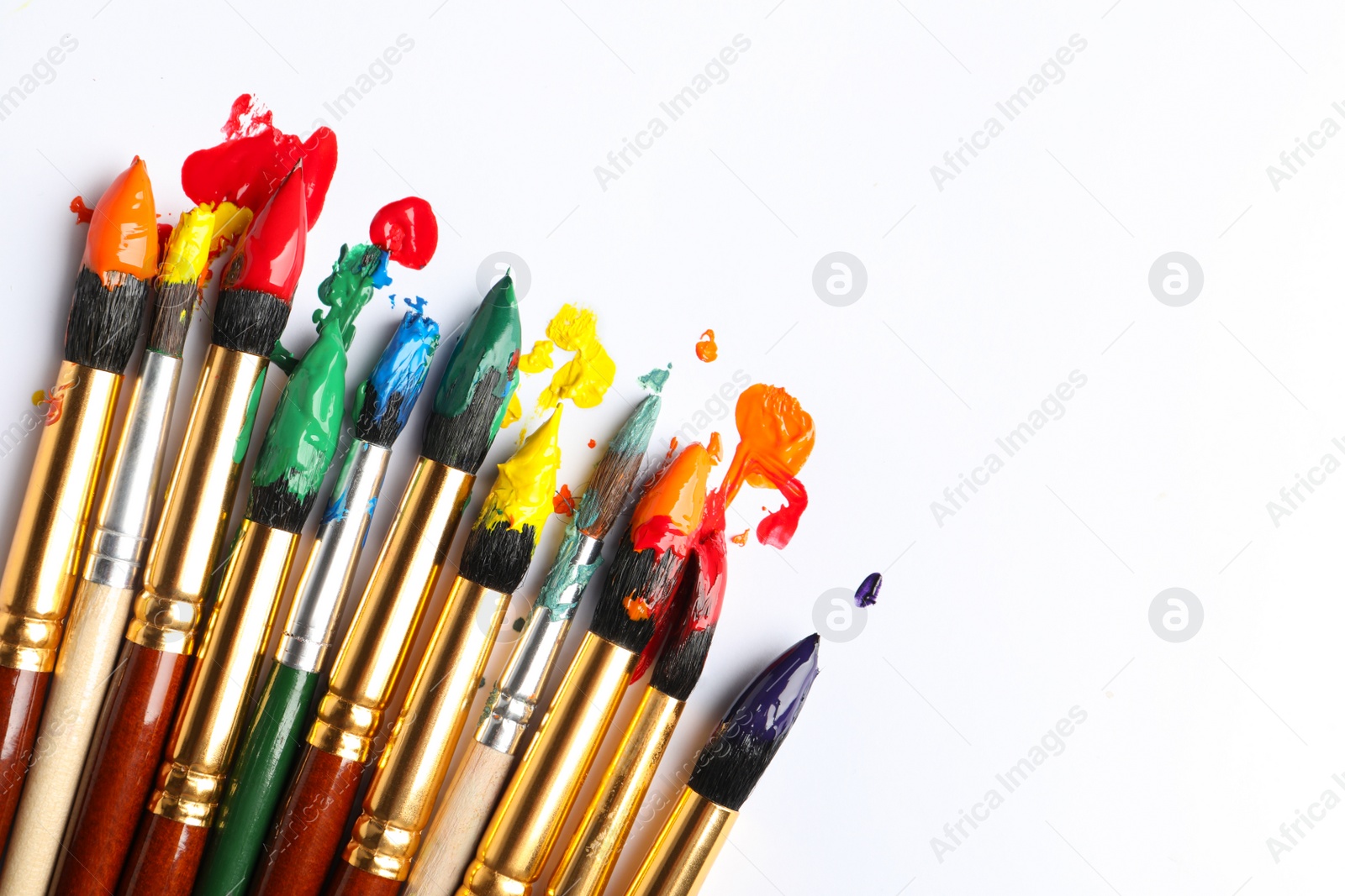 Photo of Brushes with colorful paints on white background, flat lay. Space for text