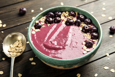 Photo of Bowl with tasty acai smoothie on wooden table