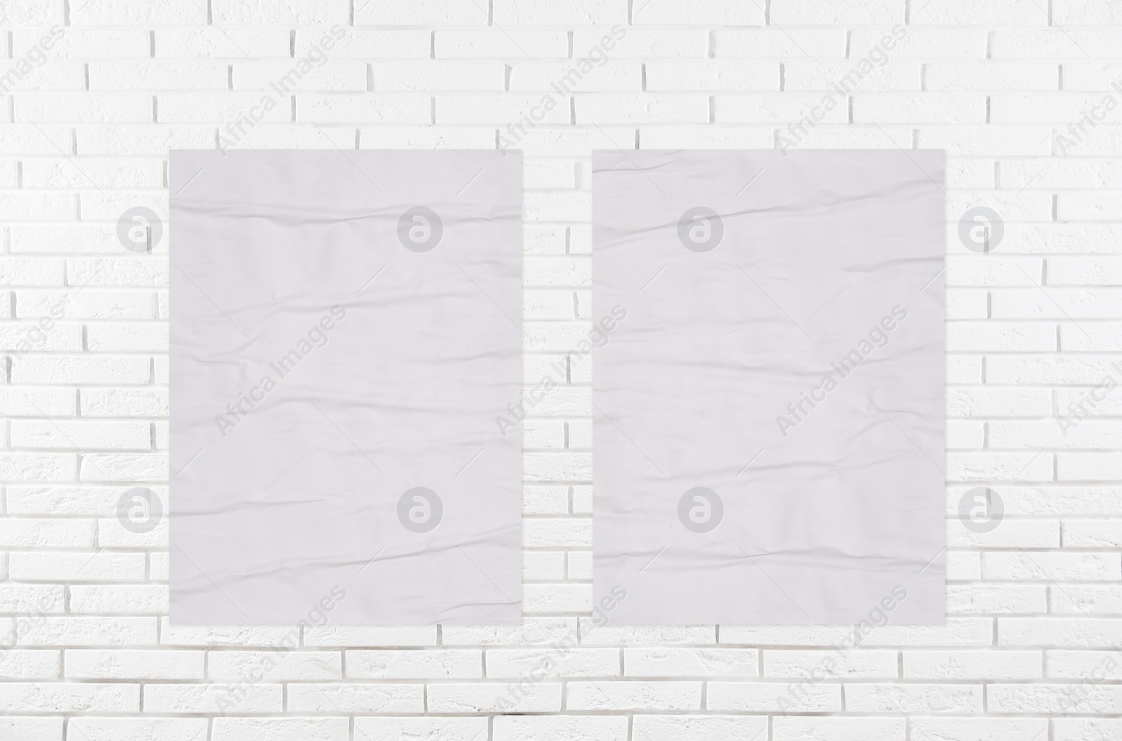 Image of Blank creased posters on white brick wall. Mockup for design 