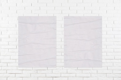 Image of Blank creased posters on white brick wall. Mockup for design 