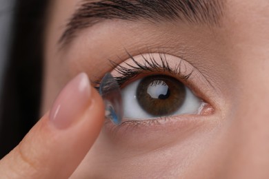 Photo of Closeup view of young woman putting in contact lens