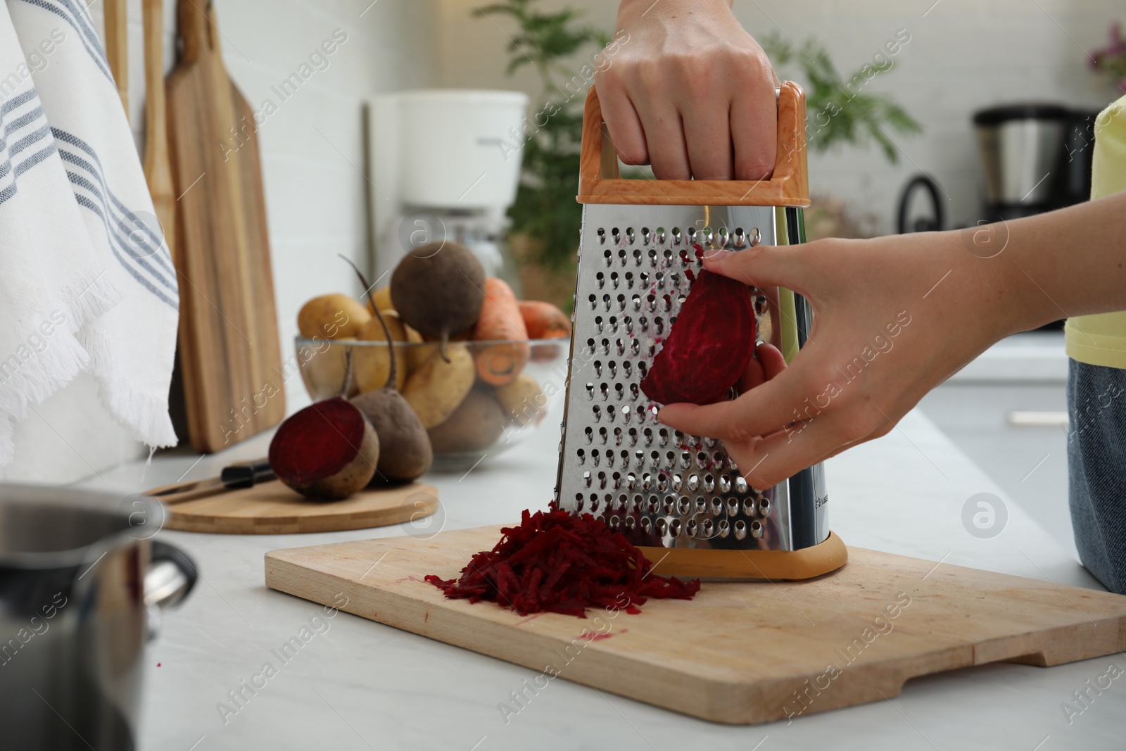 Photo of Woman grating fresh beetroot at kitchen counter, closeup