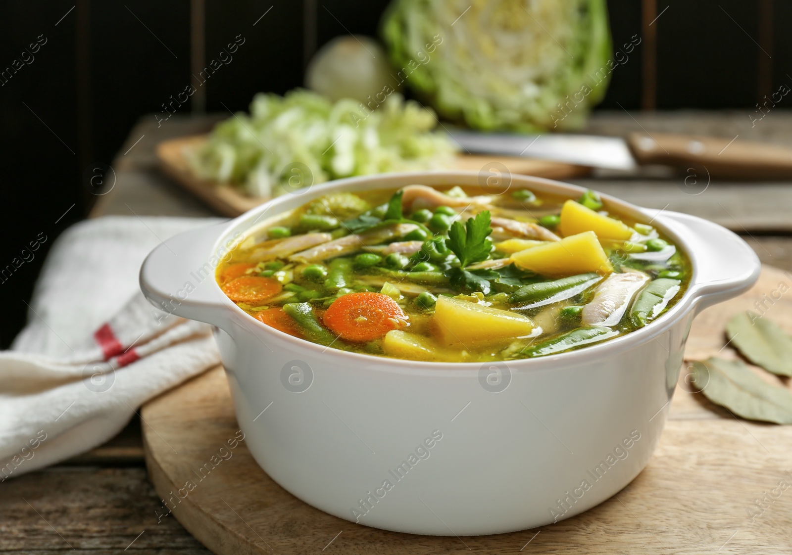 Photo of Saucepan of delicious vegetable soup with chicken on wooden table