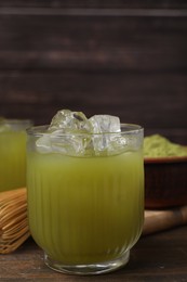 Photo of Glass of delicious iced green matcha tea on wooden table, closeup. Space for text