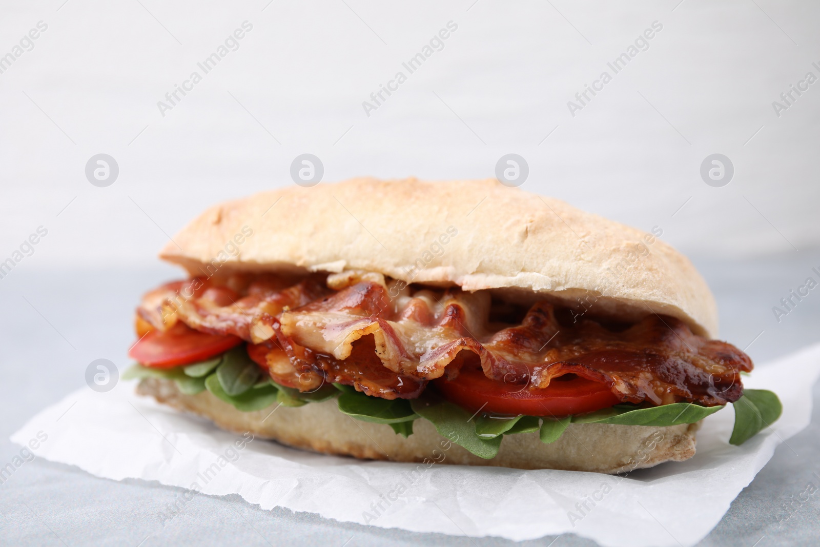 Photo of Tasty sandwich with bacon on grey table, closeup