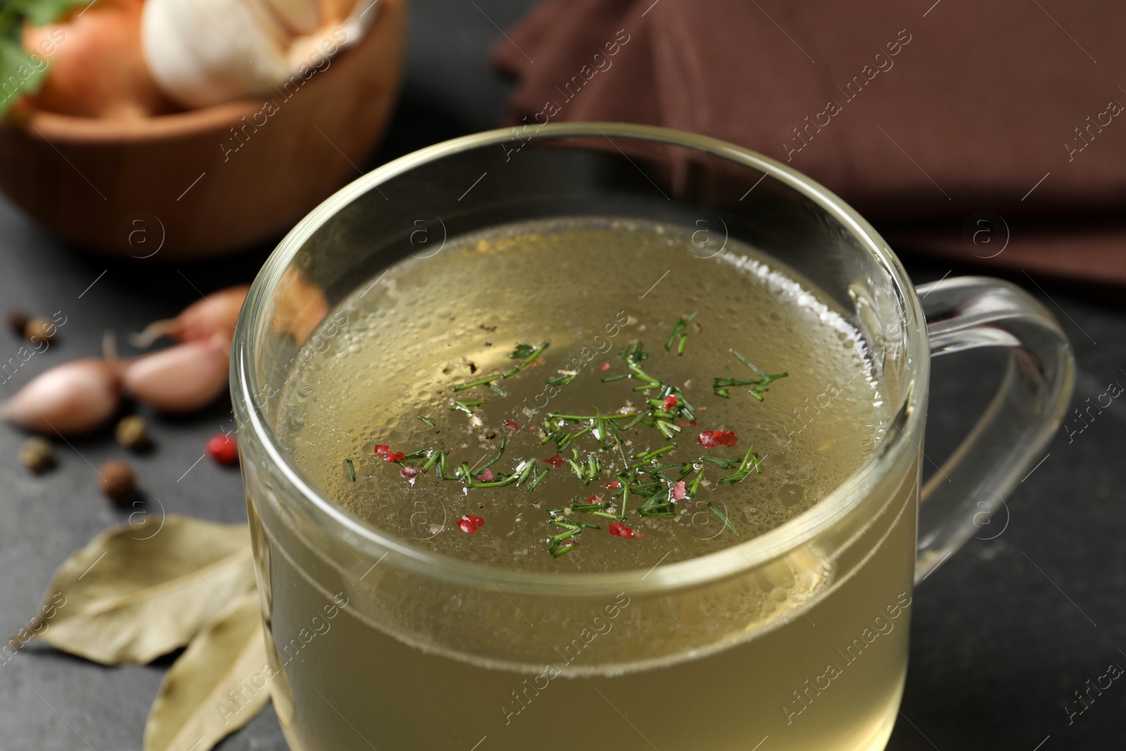 Photo of Hot delicious bouillon with dill in glass cup, closeup