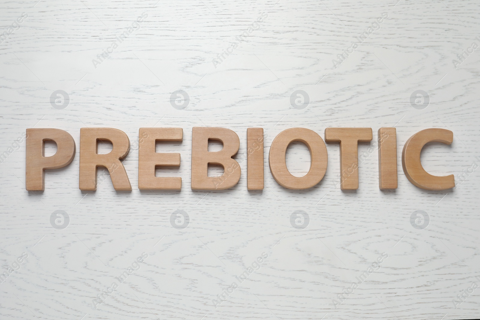 Photo of Word Prebiotic made of wooden letters on white table, flat lay