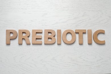 Photo of Word Prebiotic made of wooden letters on white table, flat lay