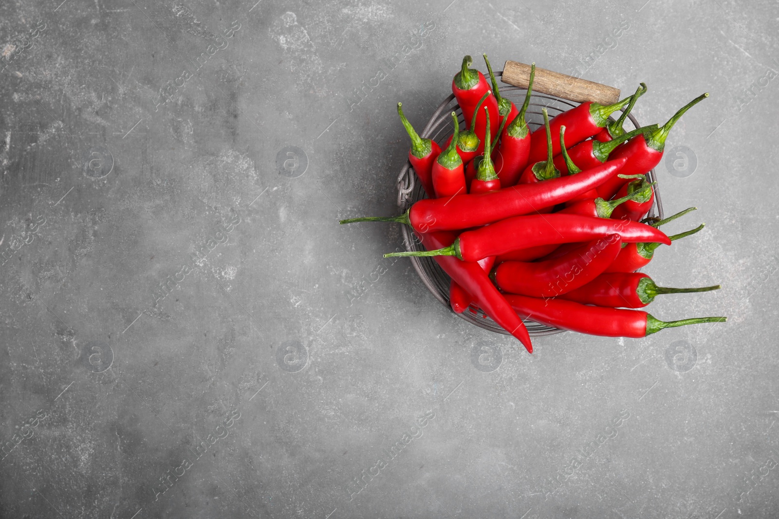 Photo of Basket with ripe chili peppers on grey background, top view