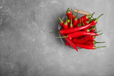 Basket with ripe chili peppers on grey background, top view