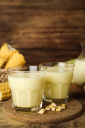 Photo of Tasty fresh corn milk in glasses on wooden table