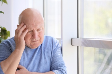 Photo of Depressed senior man near window indoors
