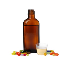 Pills, bottle with measuring cup of syrup on white background. Cough and cold medicine