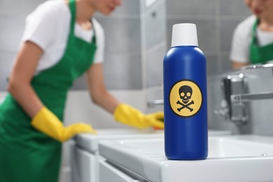 Photo of Bottle of toxic household chemical with warning sign in bathroom