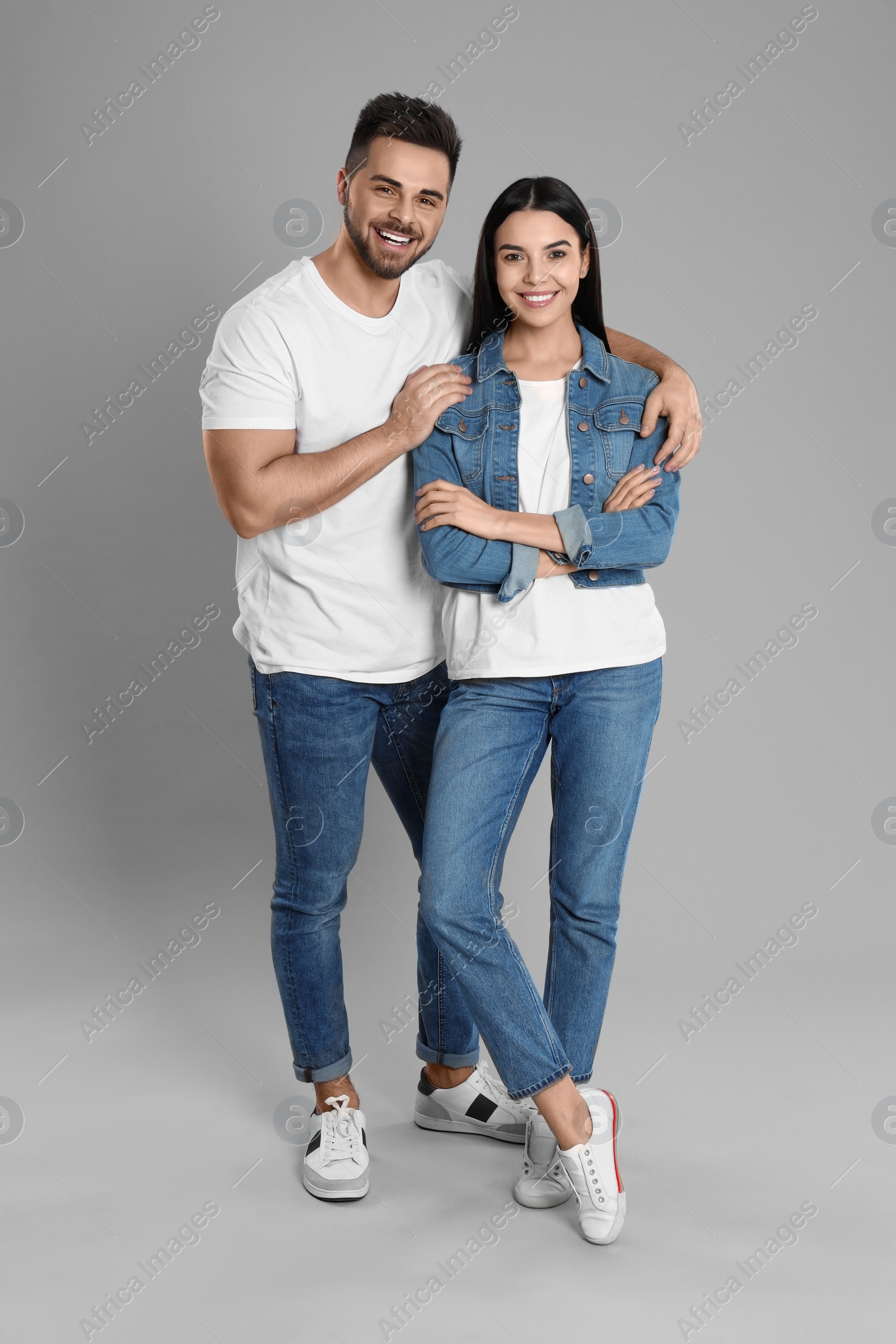 Photo of Young couple in stylish jeans on grey background