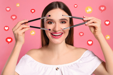Beauty blogger with makeup brushes on pink background