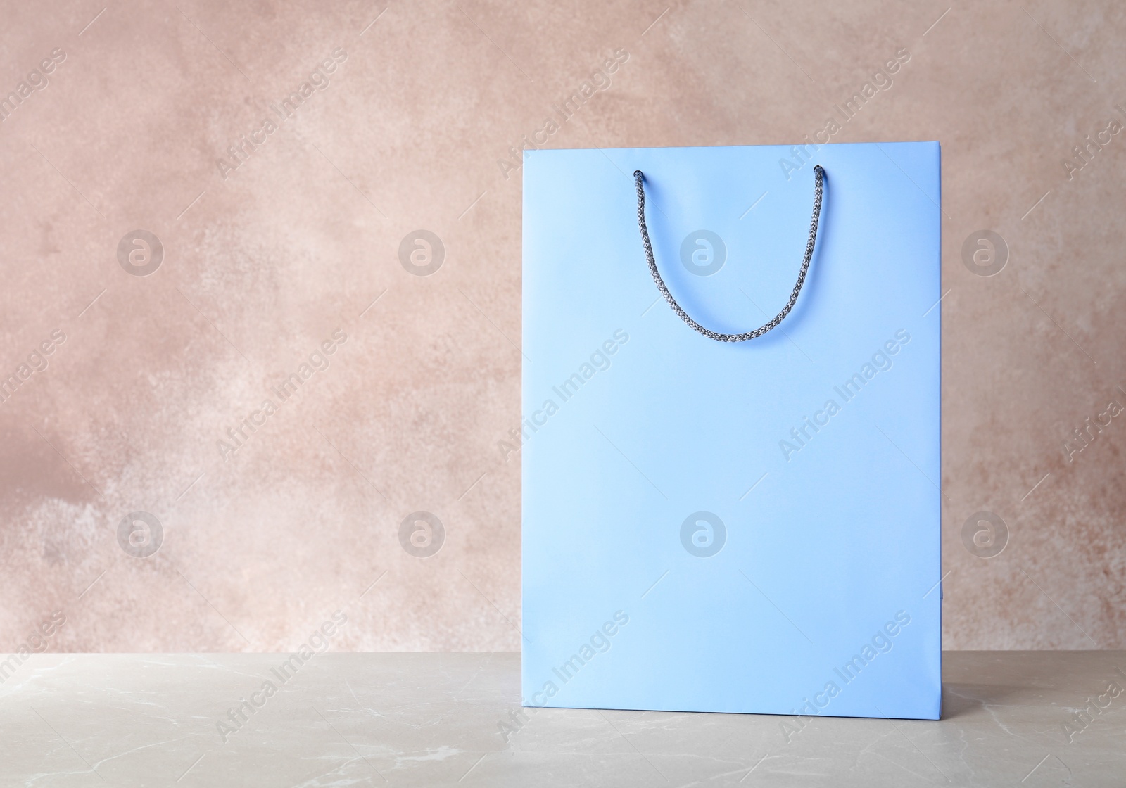 Photo of Mockup of paper shopping bag on table against color background