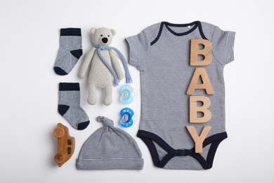 Photo of Flat lay composition with child's clothes and word Baby on white table