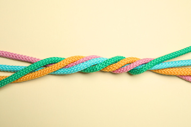 Photo of Twisted colorful ropes on beige background, top view. Unity concept