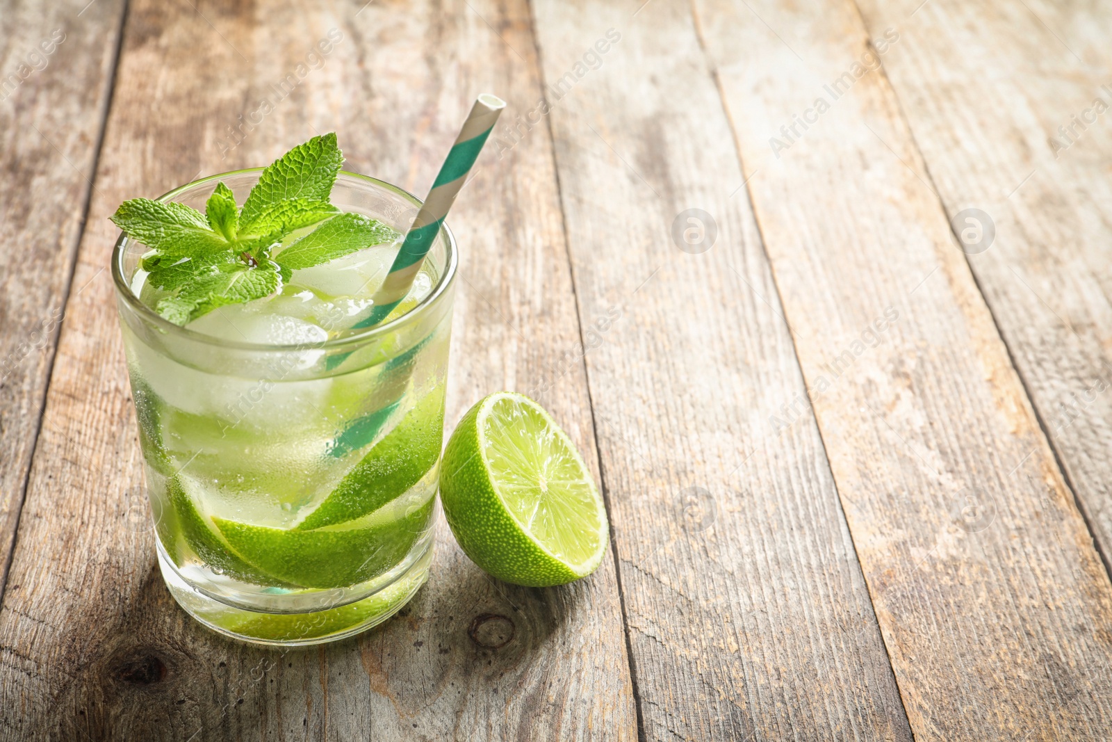 Photo of Refreshing beverage with mint and lime in glass on table