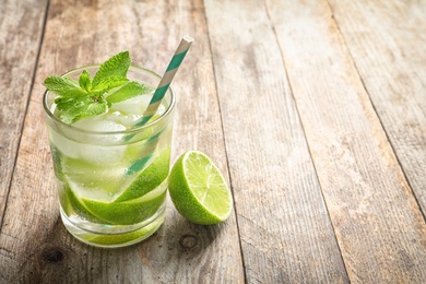 Refreshing beverage with mint and lime in glass on table