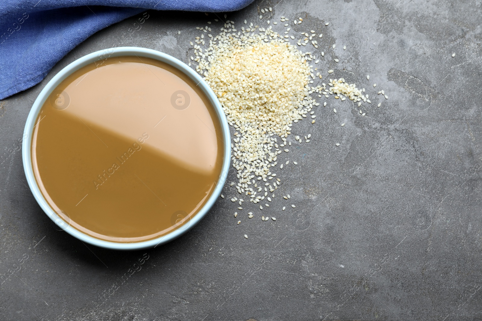 Photo of Tasty sesame paste and seeds on grey table, flat lay. Space for text