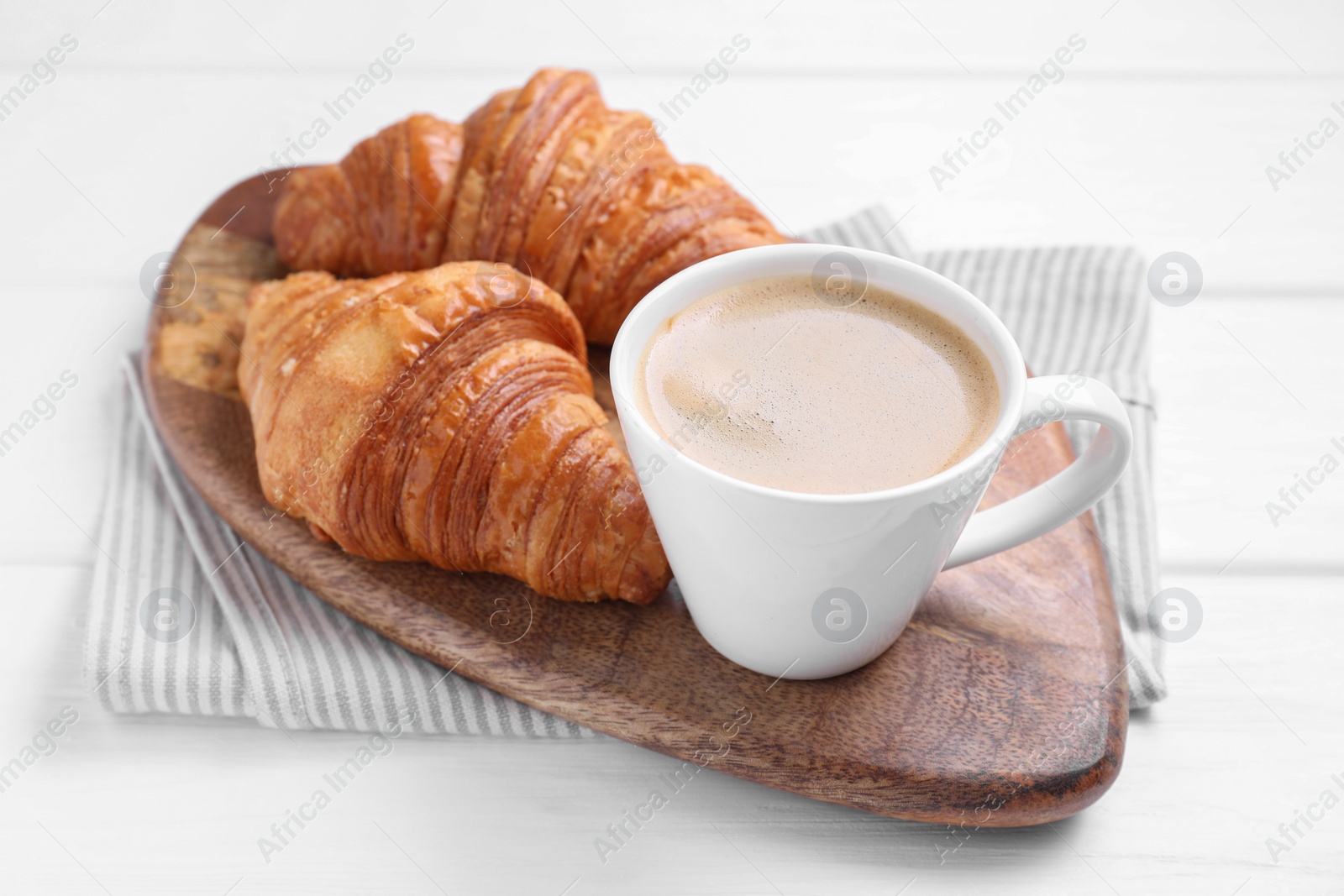 Photo of Tasty breakfast. Cup of coffee and croissants on white wooden table