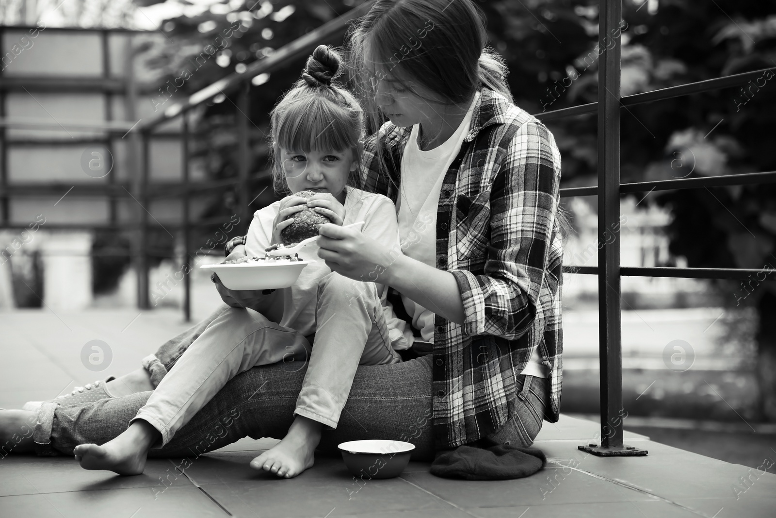 Photo of Poor people eating donated food on street, black and white effect