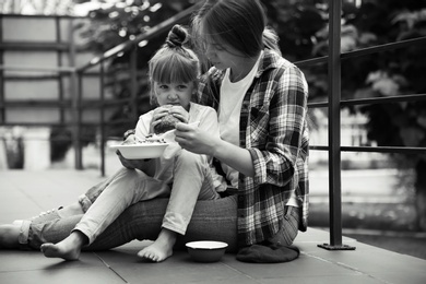 Poor people eating donated food on street, black and white effect