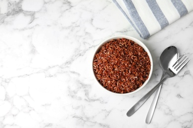 Photo of Flat lay composition with delicious cooked brown rice on white marble table. Space for text