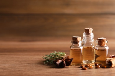 Anise essential oil and spices on wooden table, space for text