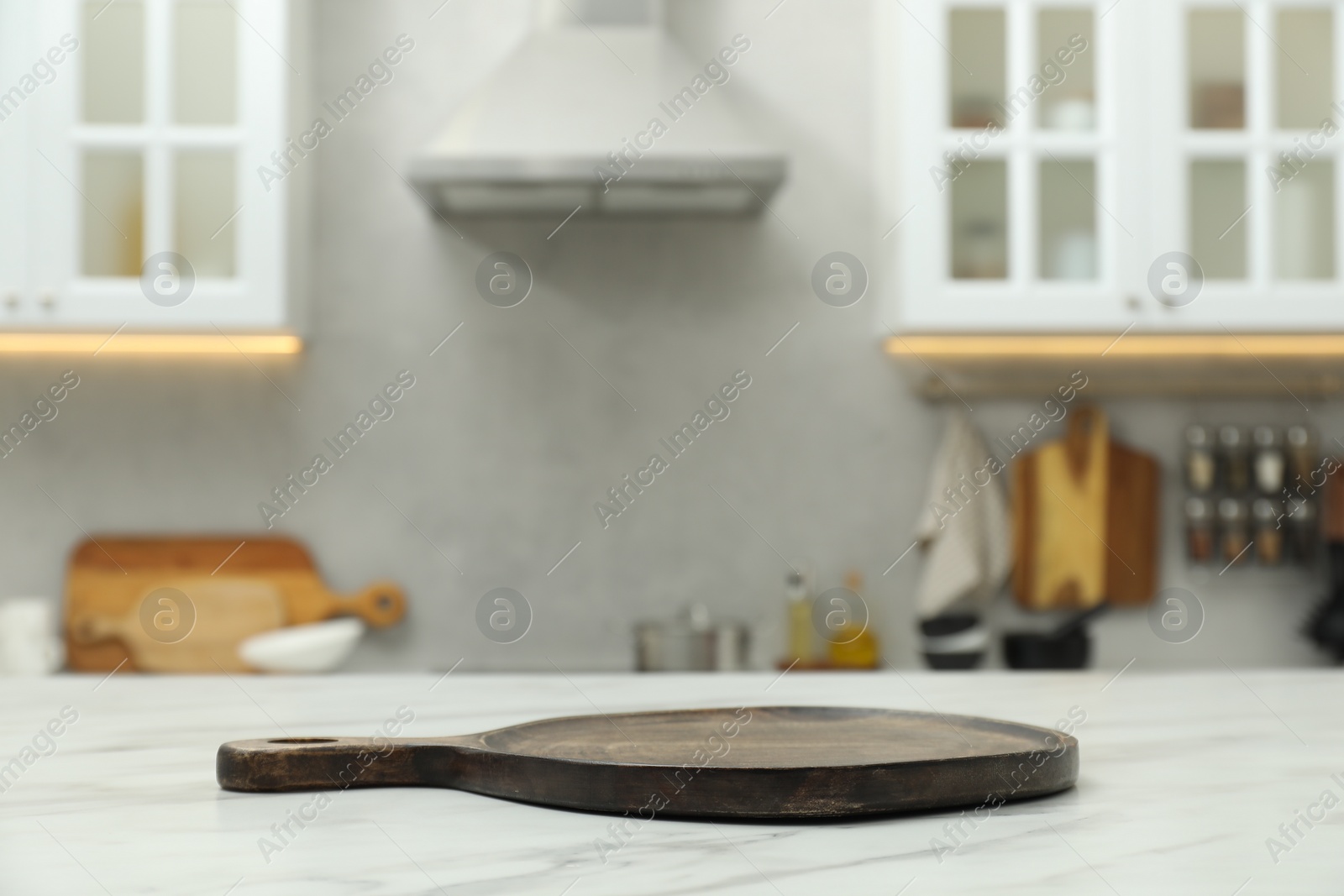 Photo of Wooden cutting board on white table in kitchen. Space for text