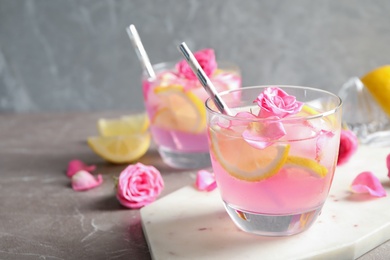 Photo of Delicious refreshing drink with lemon and roses on marble table