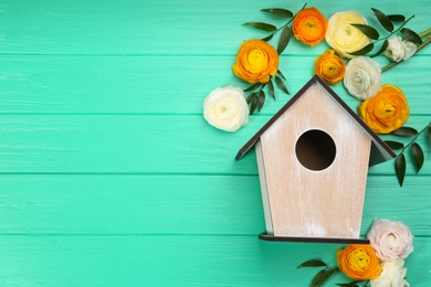 Stylish bird house and fresh eustomas on turquoise wooden background, flat lay. Space for text