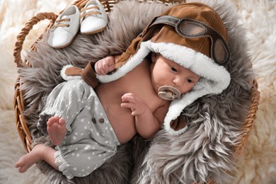 Photo of Adorable newborn baby with pacifier in wicker basket, top view