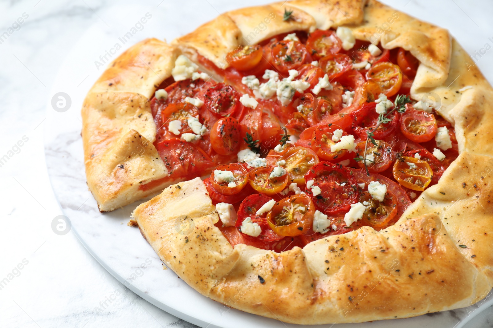 Photo of Tasty galette with tomato, thyme and cheese (Caprese galette) on white table, closeup