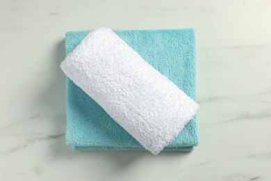 Photo of Clean folded towels on white marble table, top view