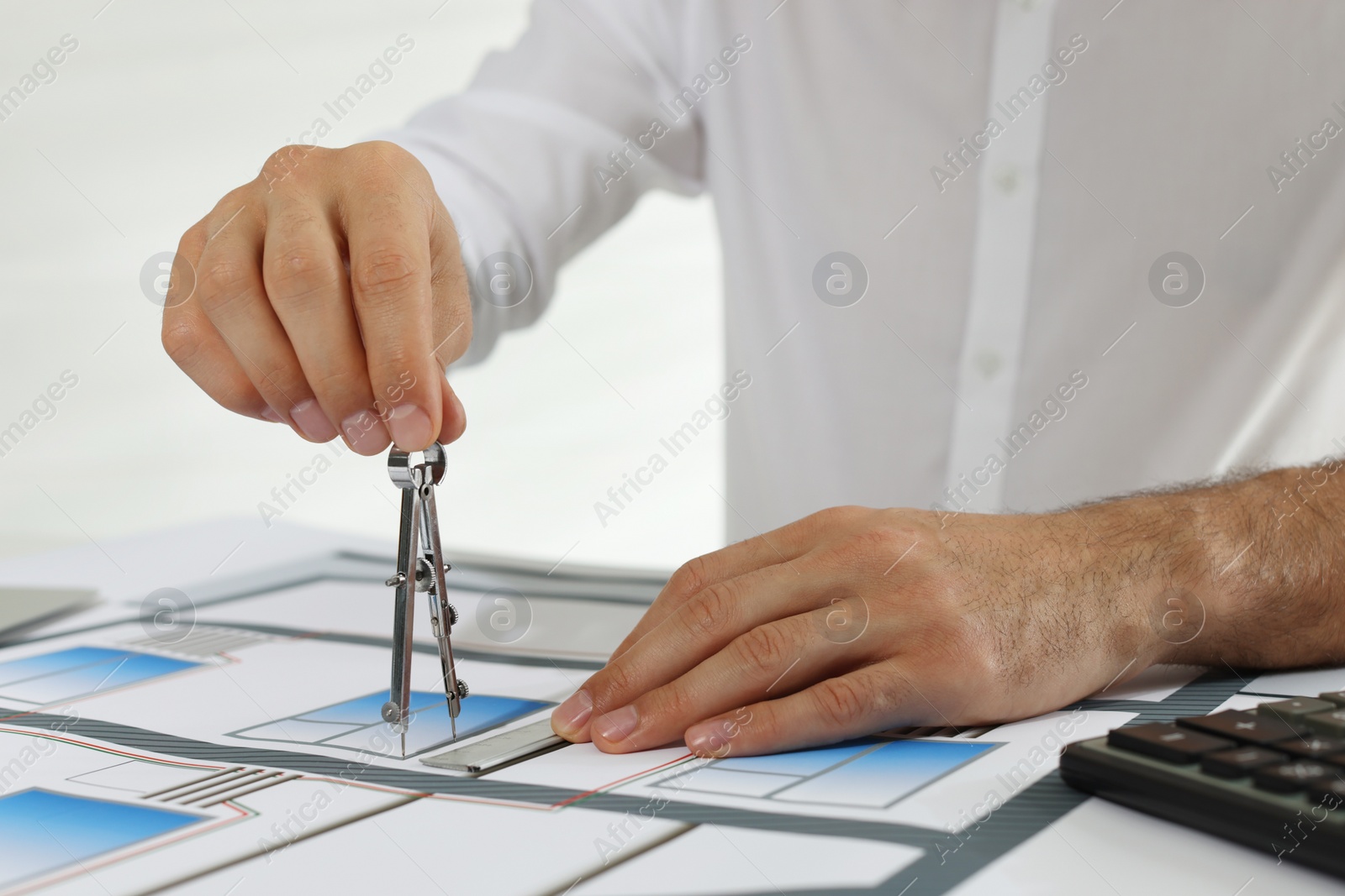 Photo of Architect working with construction drawings indoors, closeup