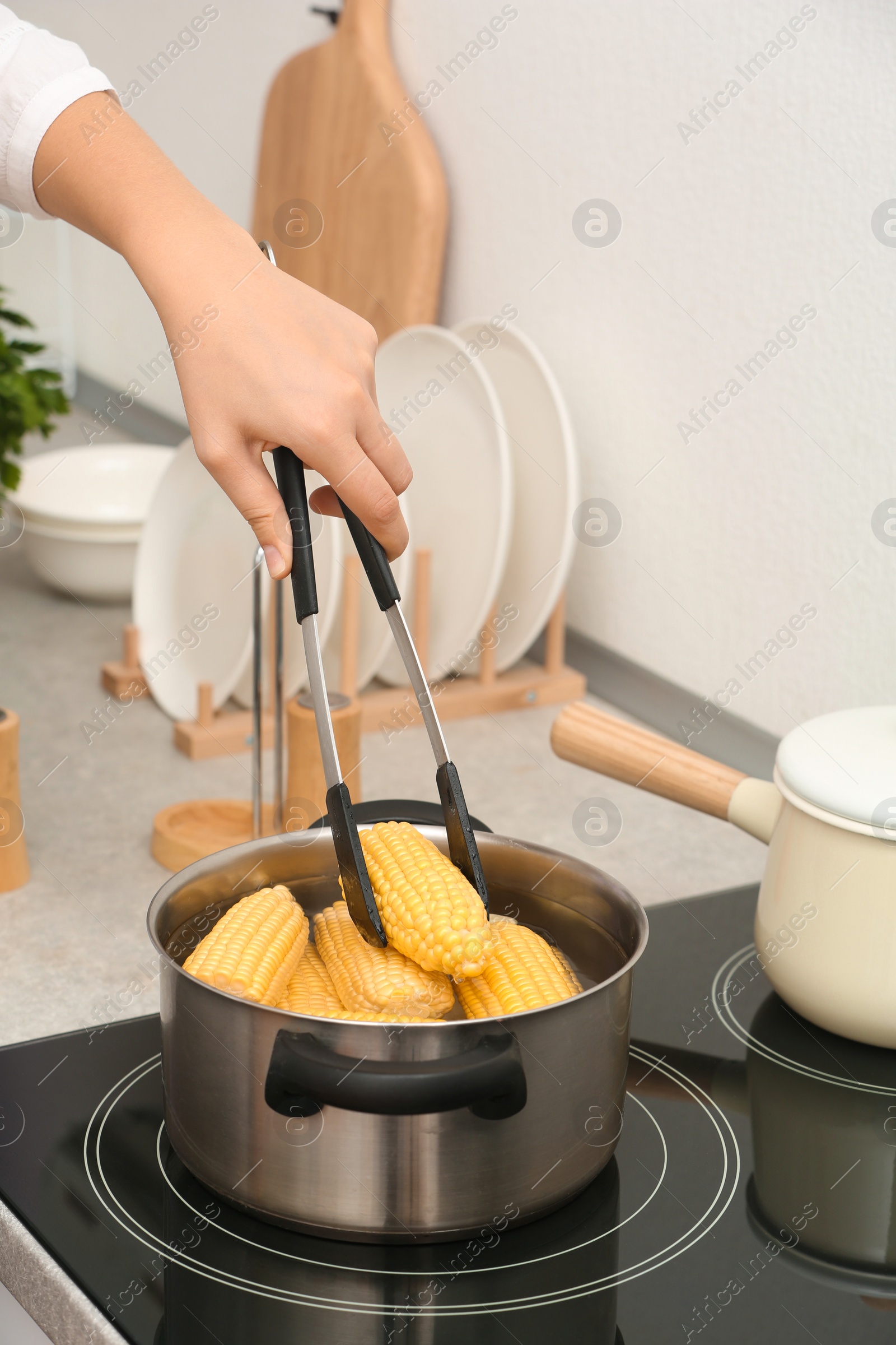 Photo of Woman preparing corn in stewpot on stove, closeup