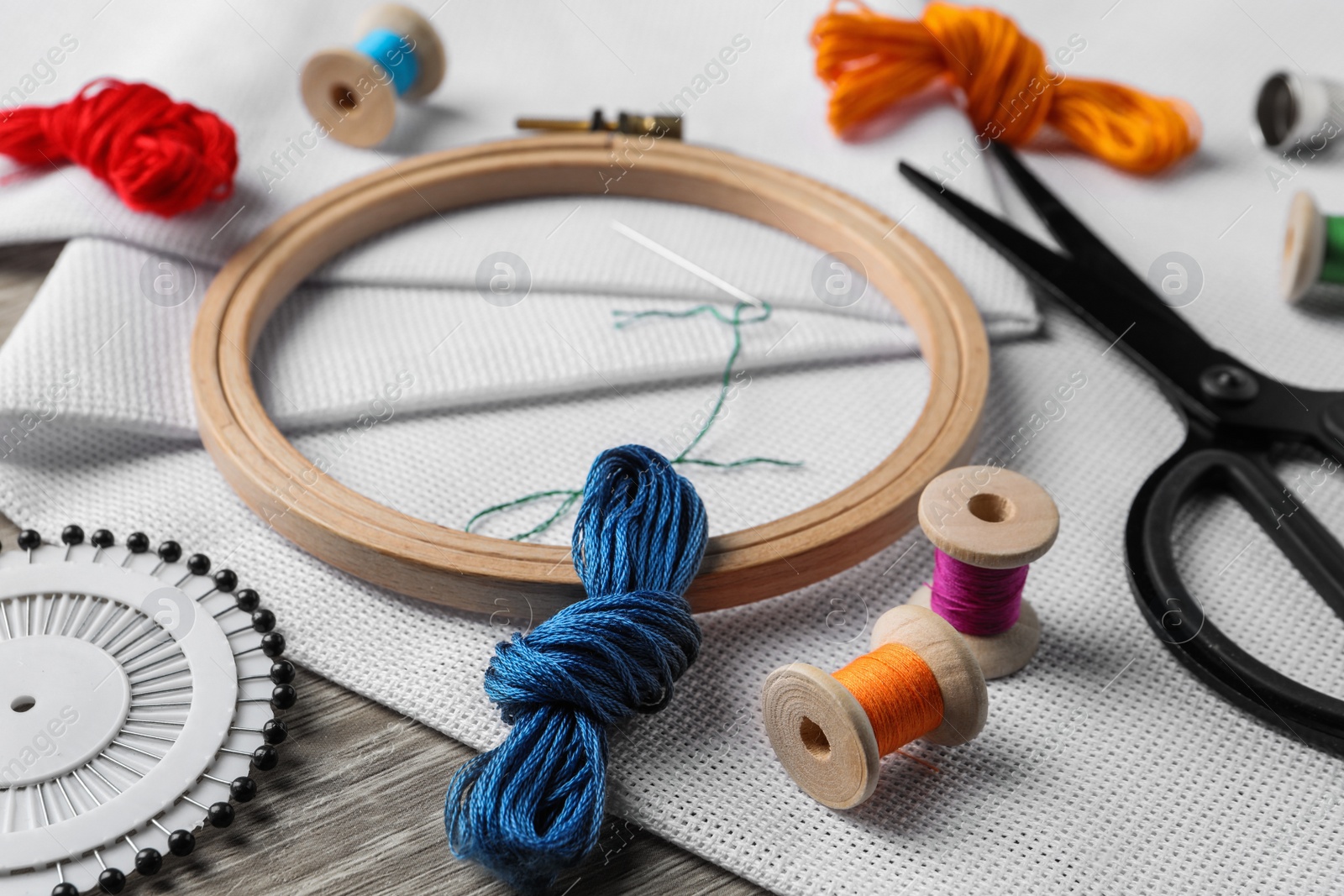 Photo of Embroidery hoop, fabric and other accessories on wooden table